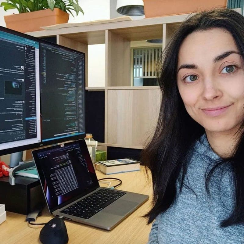 A girl programmer next to a monitor with code on it